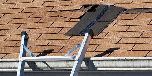 Damaged shingle roof with a patch in ready to be installed.